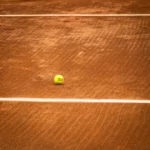 Balle de tennis posée sur une ligne blanche de court en terre battue