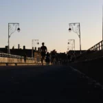 Coureurs traversant un pont urbain au coucher du soleil
