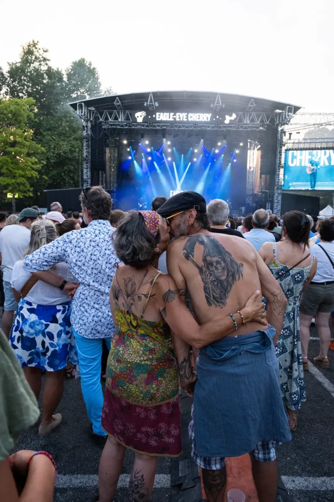 Couple de spectateurs enlacés face à une scène de concert lors d’un festival