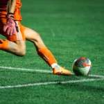 Détail du ballon et des crampons lors d’une action de football