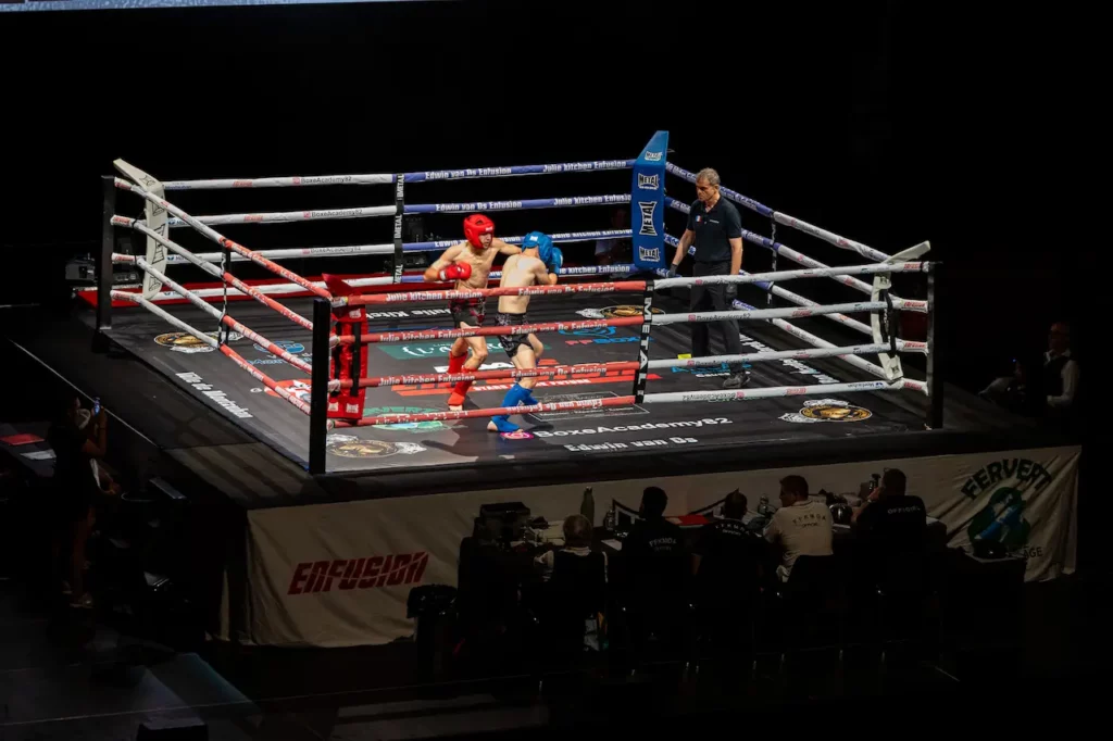 Vue d’ensemble d’un ring de boxe éclairé pendant un combat lors d’un gala sportif à Montauban.