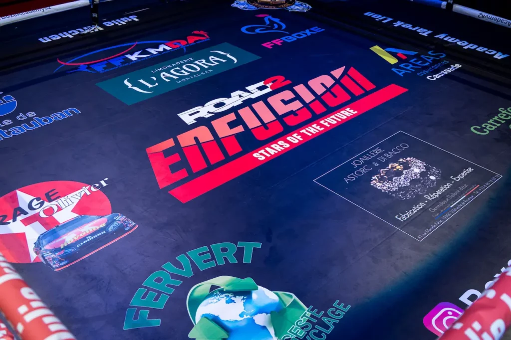 Tapis de ring avec logos de sponsors pendant un gala de sports de combat à Montauban.