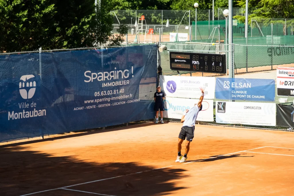 Joueur de tennis au service vu sous un angle dynamique à Montauban