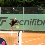 Joueur de tennis exécutant un service sur un court en terre battue à Montauban