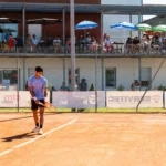 Joueur de tennis sur terre battue avec le public en tribune lors d’un tournoi à Montauban