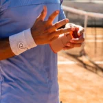Joueur de tennis ajustant son strap avant un match sur terre battue à Montauban