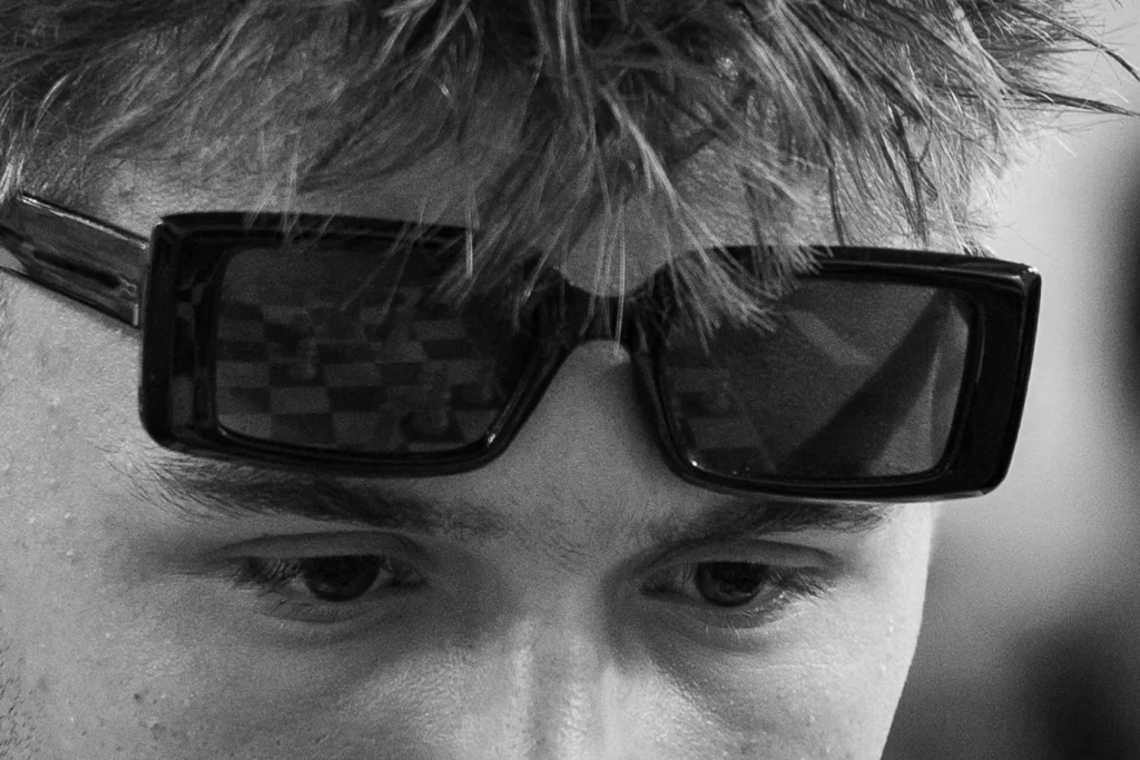 Reflet d’un échiquier dans les lunettes relevées sur le front d’un jeune joueur