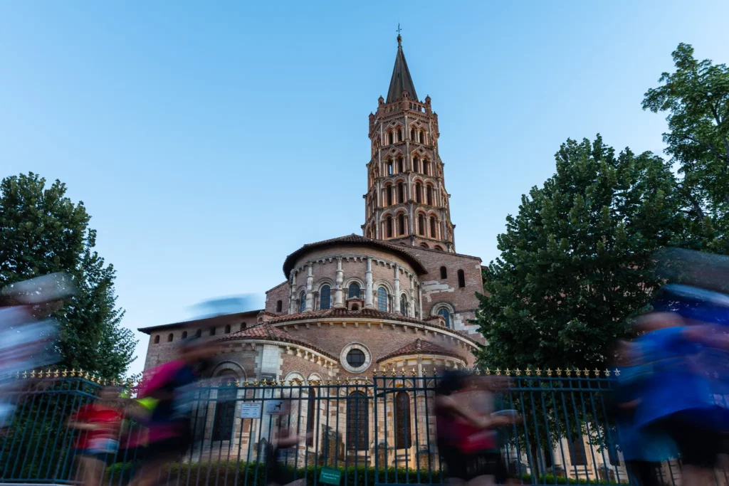 Coureurs en mouvement devant la basilique Saint-Sernin pendant une course à Toulouse